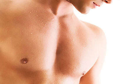 Picture of a man looking slightly away from the camera showing his chest and happy with his perfect male breast reduction procedure he had at Top Plastic Surgeons in beautiful San Jose, Costa Rica.  The man is shirtless and is looking downwards.
