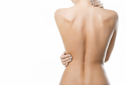 Picture of a woman with her back to the camera, happy with her perfect upper body lift procedure she had at Top Plastic Surgeons in beautiful San Jose, Costa Rica.  The woman has one hand on her neck and the other hand on her side showing the results of her upper body lift.