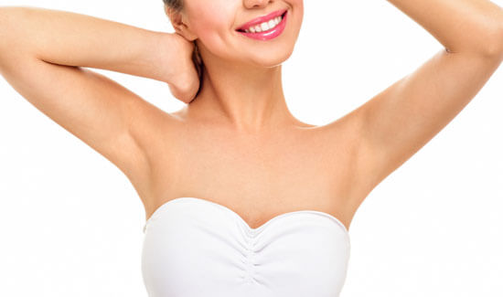 Picture of a woman holding her arms up and happy with her perfect arms liposuction procedure she had at Top Plastic Surgeons in beautiful San Jose, Costa Rica.  The woman is wearing a white top and smiling to the camera.